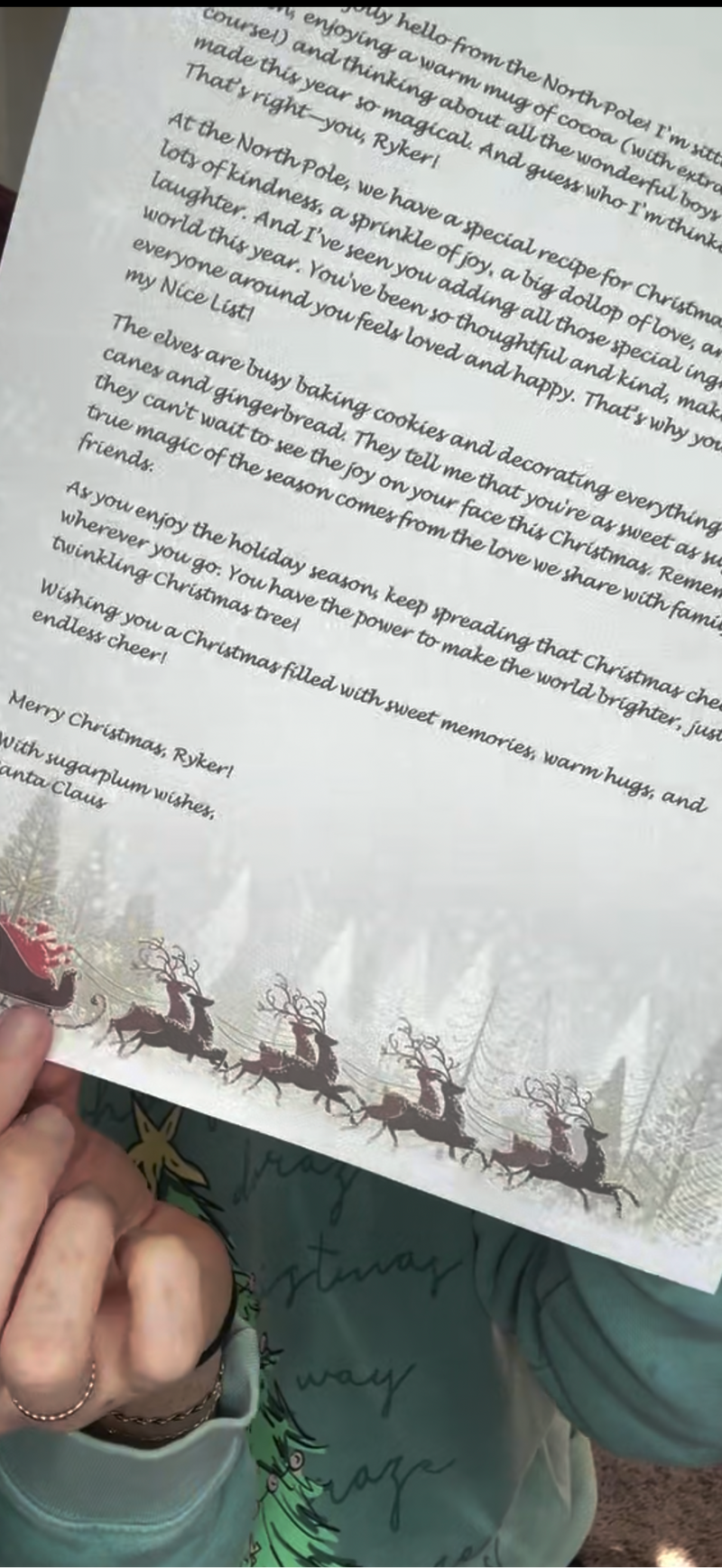 Mom holding printed Santa letter featuring sleigh and reindeer illustration at the bottom