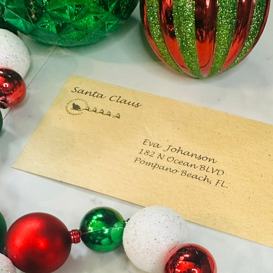 Decorative wreath with red, green, and white ornaments on a white surface with a letter from Santa Claus.